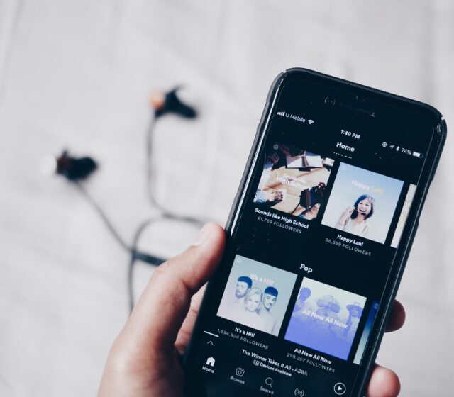 hand holding a mobile phone showing Spotify app