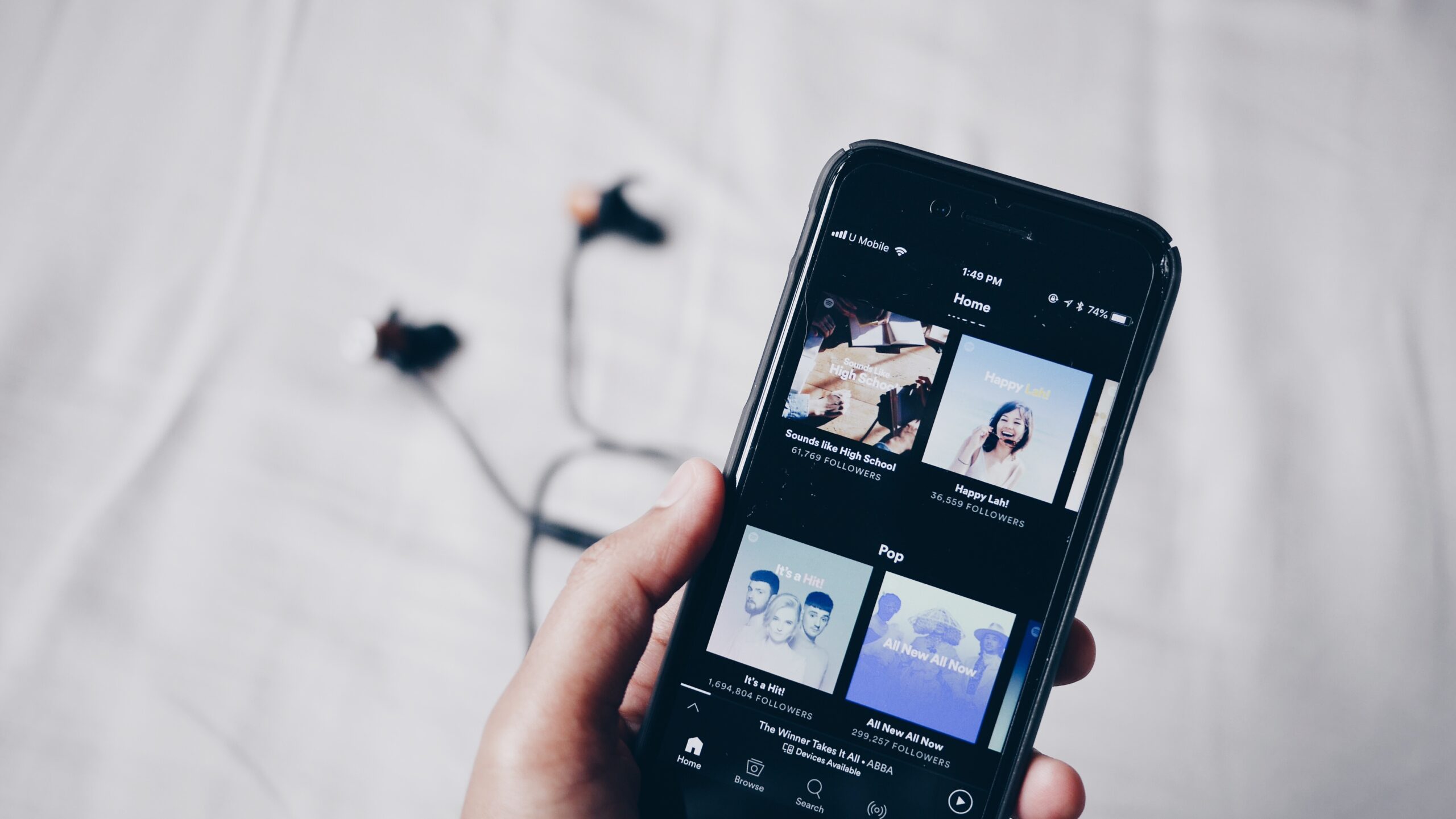 hand holding a mobile phone showing Spotify app